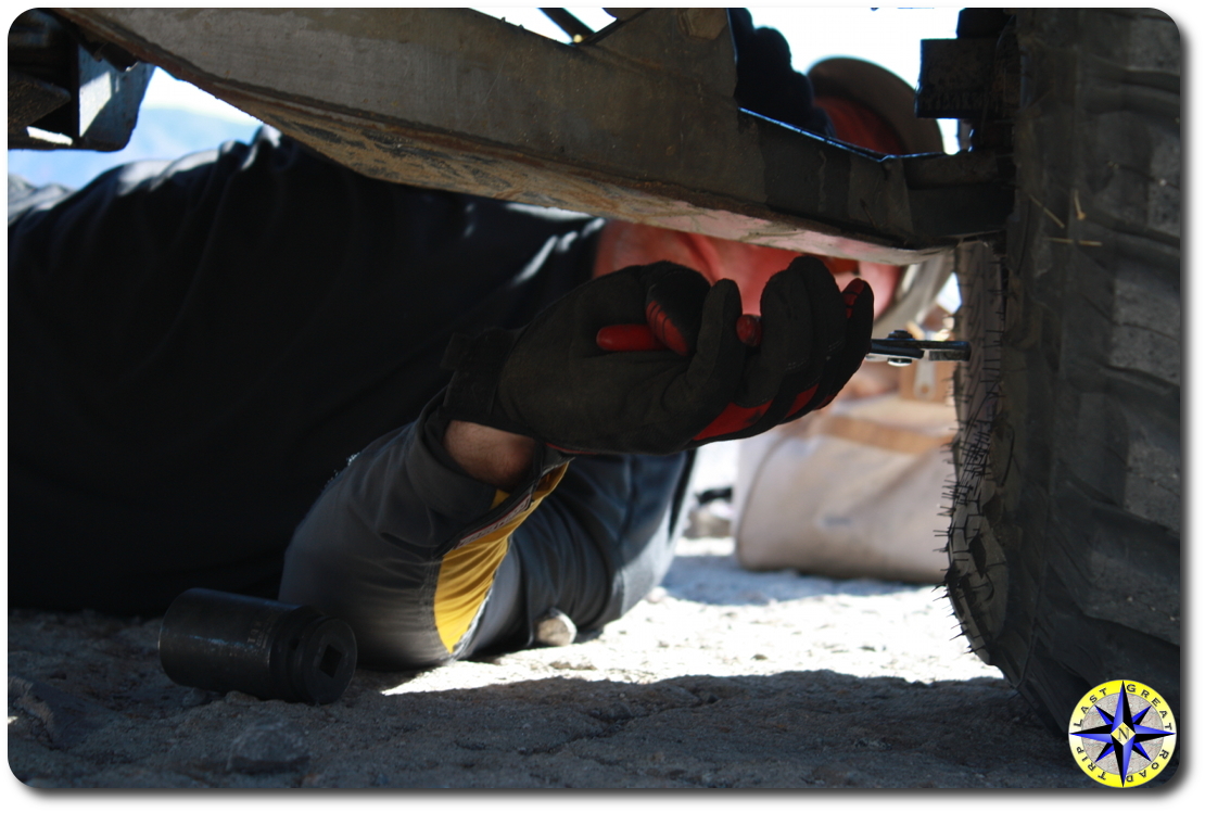 man inspecting truck suspension in sand