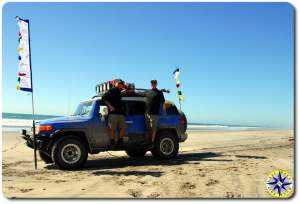 two men standing on fj cruiser baja mexico pacific beach prayer flags